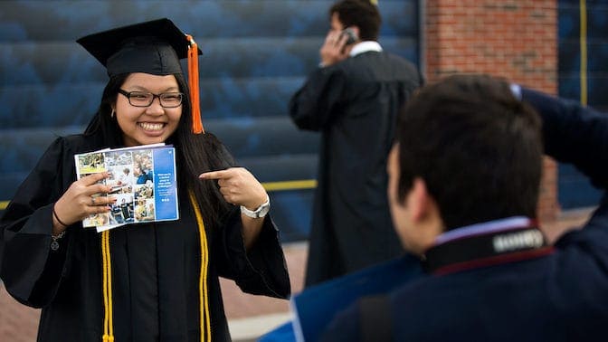 Graduate in cap and gown smiles for a photo