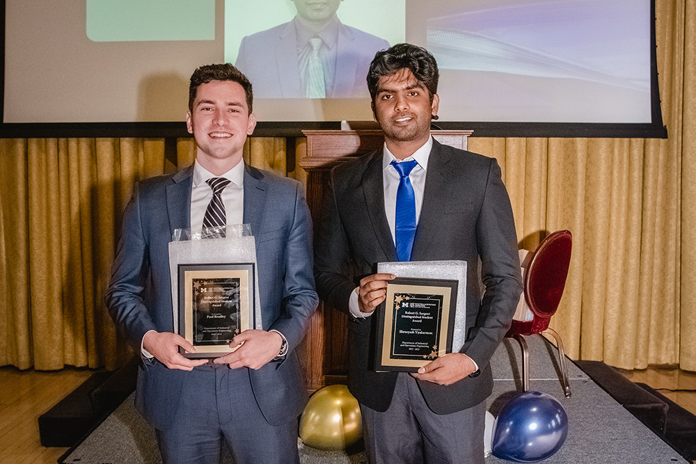 Two people smiling hold an award