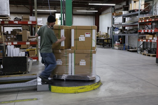 A worker stacks large boxes in a warehouse.