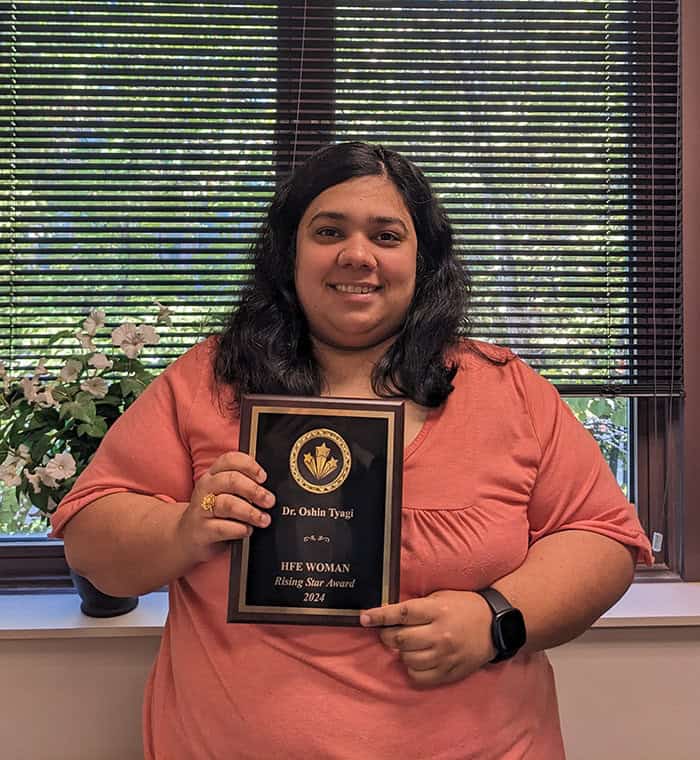 Oshin Tyagi holds a plaque naming her a rising woman of the year at HFES.