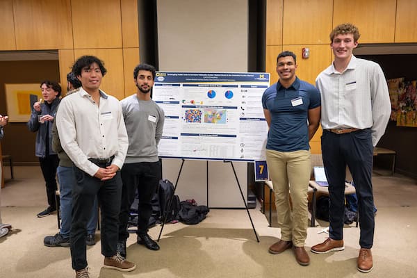 Four students pose for a photo with their research poster. 