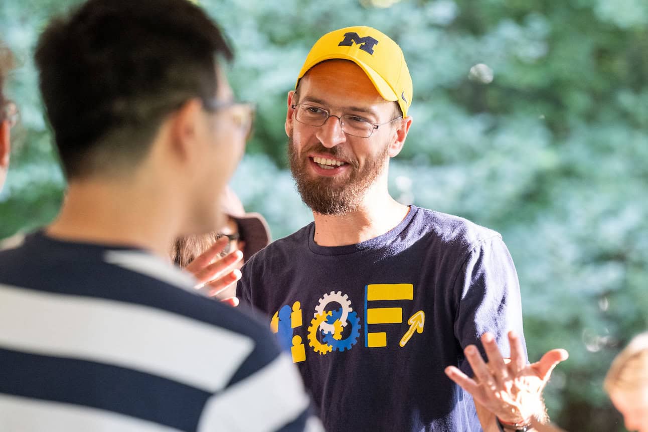 Albert S. Berahas speaks to a person blurred in the foreground.